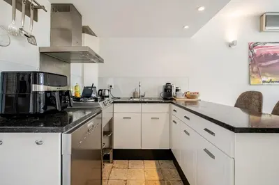 a kitchen with white cabinets and black counter tops at Charming Loft with Free Parking and 15 mins to AMS in Vinkeveen