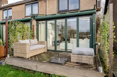 a glass conservatory with a couch and chairs on a deck at Charming Loft with Free Parking and 15 mins to AMS in Vinkeveen