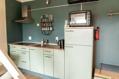 a kitchen with a sink and a microwave on top of a refrigerator at De Stranding Nieuw in Egmond aan den Hoef