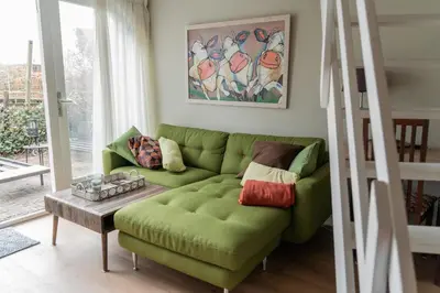 a living room with a green couch and a table at De Stranding Nieuw in Egmond aan den Hoef