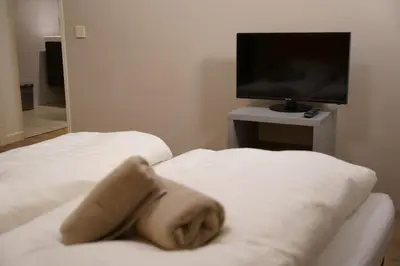 a room with two white beds and a television at Lighthouse Beach Apartment in Noordwijk aan Zee