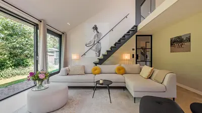 a living room with two couches and a staircase at Villa Zonnelicht in Bergen