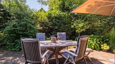 a wooden table with chairs and an umbrella at Villa Zonnelicht in Bergen