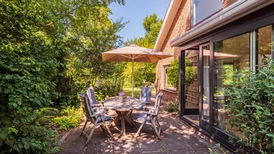 a patio with a table and chairs and an umbrella at Villa Zonnelicht in Bergen
