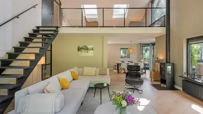 a living room with a couch and a staircase at Villa Zonnelicht in Bergen