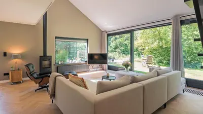 a living room with a large couch and large windows at Villa Zonnelicht in Bergen