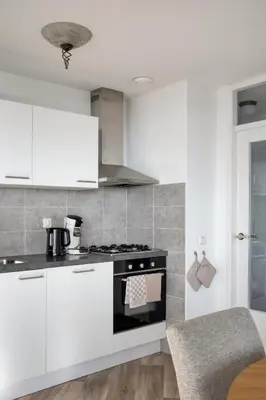 a kitchen with white cabinets and a stove top oven at Comfortable Stay Close To The Coast in Burgerbrug