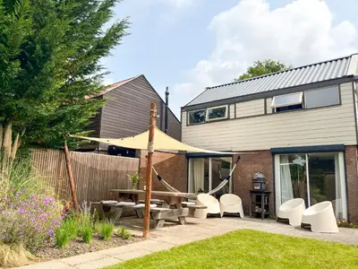 a house with a patio with a table and chairs at Strandbries in Warmenhuizen