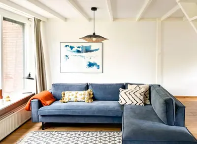 a blue couch in a living room with a window at Strandbries in Warmenhuizen