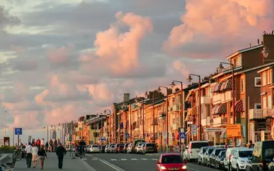a city street with cars and people walking down the street at Skip Inn Strandhuisjes in Katwijk aan Zee