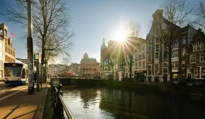 a river in a city with the sun shining at Supper Boutique Suites in Amsterdam
