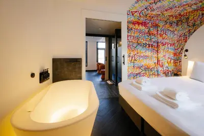 a bathroom with a bath tub and a bed at Supper Boutique Suites in Amsterdam