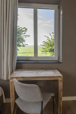 a table and a chair in front of a window at Hotelboerderij Akkerlust in Leidschendam