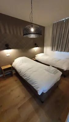 a bedroom with two beds and a pendant light at Hotelboerderij Akkerlust in Leidschendam