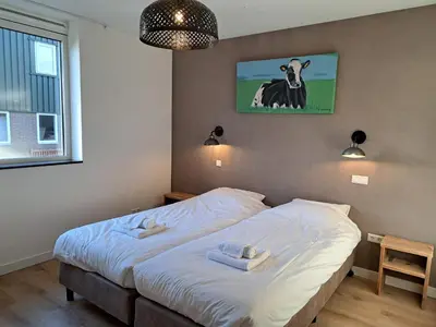 a bed in a bedroom with a picture of a cow at Hotelboerderij Akkerlust in Leidschendam