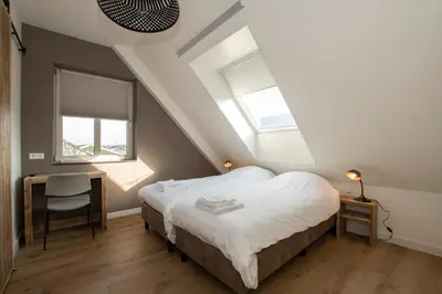 a bedroom with a bed and a desk and windows at Hotelboerderij Akkerlust in Leidschendam