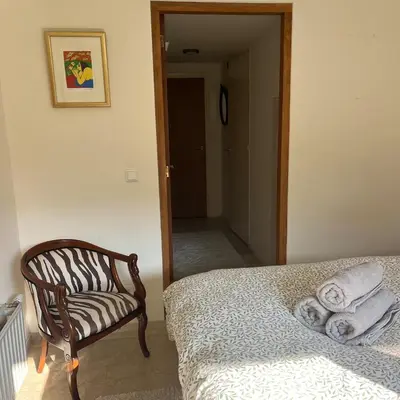 a bedroom with a bed and a chair and a hallway at Cosy Garden Room Riverhouse in Ouderkerk aan de Amstel