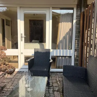 a patio with two chairs and a table in front of a door at Cosy Garden Room Riverhouse in Ouderkerk aan de Amstel