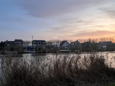 a group of houses next to a body of water at Cosy Garden Room Riverhouse in Ouderkerk aan de Amstel