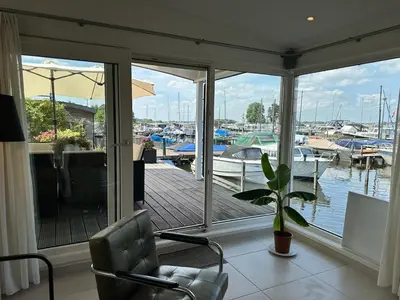 a living room with a view of a marina at Houseboat the Otter incl free boat and supboards in Loosdrecht