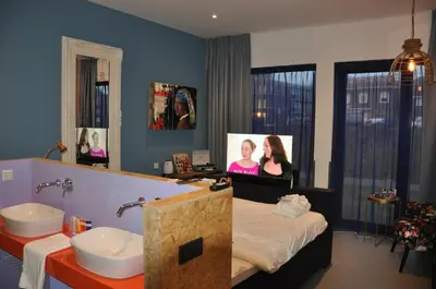 a bathroom with a bed and a sink and a mirror at Hotel Rauw aan de Kade in IJmuiden