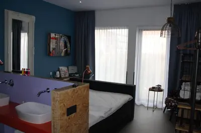 a bedroom with a bed and a sink and blue walls at Hotel Rauw aan de Kade in IJmuiden