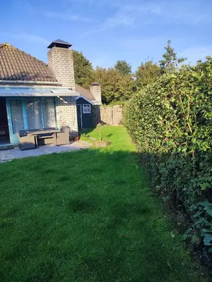 a yard next to a house with a grass yard sidx sidx at Gemütliches, komfortables Ferienhaus in Schoorl