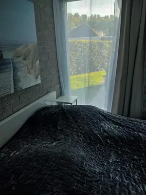 a bedroom with a bed and a large window at Gemütliches, komfortables Ferienhaus in Schoorl