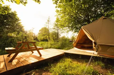 a tent and a picnic table on a wooden deck at Glamping belltent in het groen in Zeewolde