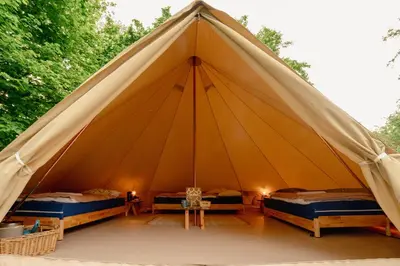 a large tent with two beds and a table at Glamping belltent in het groen in Zeewolde