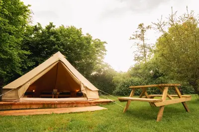 a tent and a picnic table in the grass at Glamping belltent in het groen in Zeewolde
