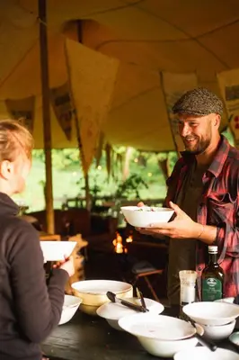 a man holding a bowl in front of a table at Glamping belltent in het groen in Zeewolde