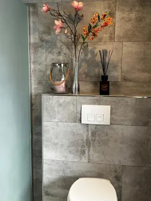 a bathroom with a toilet and flowers on a wall at Holiday home in the polder in Abcoude