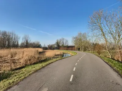 an empty road in the middle of a field at Holiday home in the polder in Abcoude