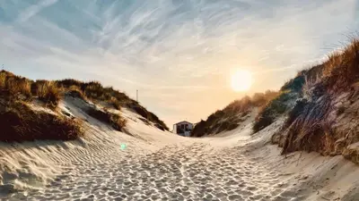 a beach with the sun setting on the sand at Spacious Eclectic Home Near Sea & Amsterdam in IJmuiden