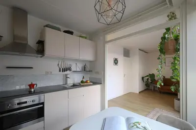 a kitchen with white cabinets and a table in a room at East-Side Living in Amsterdam