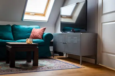 a living room with a green couch and a flat screen tv at Complete studio dichtbij Hoorn en Alkmaar in Zuidermeer