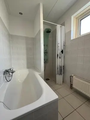 a white bathroom with a tub and a shower at Ferienhaus Aan de Gracht - IJsselmeer in Wervershoof
