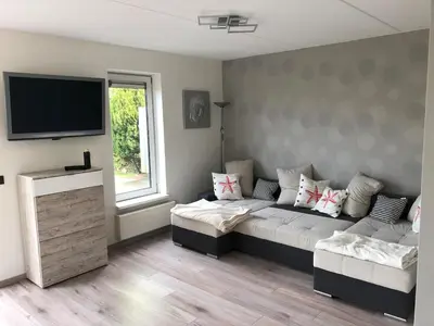 a living room with a couch and a flat screen tv at Ferienhaus Aan de Gracht - IJsselmeer in Wervershoof