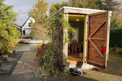 a tiny house with a door and ivy around it at Ferienhaus Aan de Gracht - IJsselmeer in Wervershoof