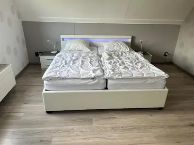 a bedroom with a bed with white sheets and pillows at Ferienhaus Aan de Gracht - IJsselmeer in Wervershoof