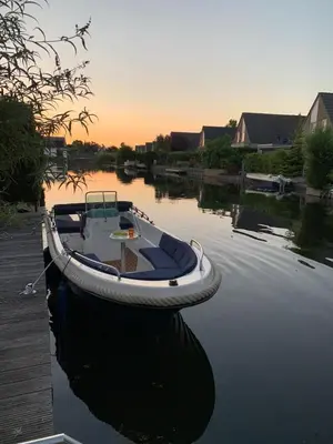 a boat tied to a dock in the water at Ferienhaus Aan de Gracht - IJsselmeer in Wervershoof