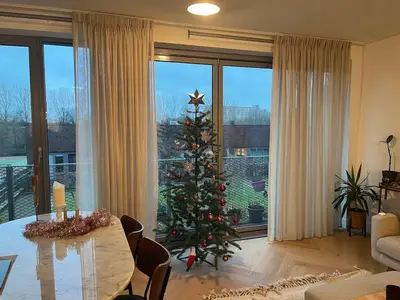 a christmas tree in a living room with a table at Spacious and modern apartment in Amsterdam