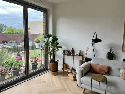 a living room with a couch and a balcony with potted plants at Spacious and modern apartment in Amsterdam
