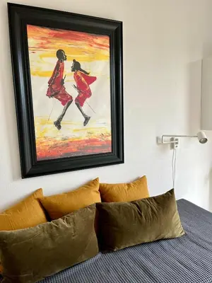 a painting on a wall above a bed with pillows at Spacious and modern apartment in Amsterdam