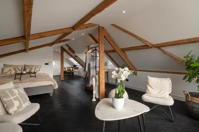a attic room with a bed and a table and chairs at Villa COCO Aphrodite Apartment in Noordwijk