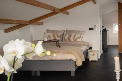 a bedroom with a bed and a table with white flowers at Villa COCO Aphrodite Apartment in Noordwijk