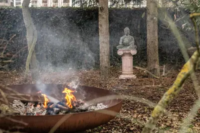 a statue of a buddha sitting in a fire pit at Villa COCO Aphrodite Apartment in Noordwijk