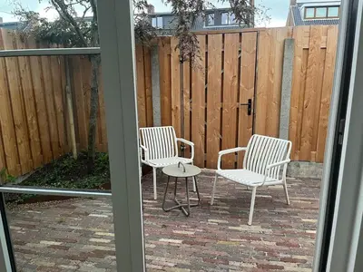 three chairs and a table in front of a fence at Ons Bijhuis in Wijk aan Zee