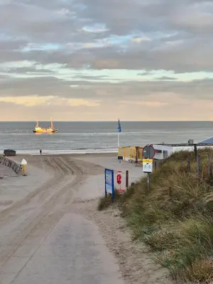 a sandy beach with a boat in the ocean at Ons Bijhuis in Wijk aan Zee